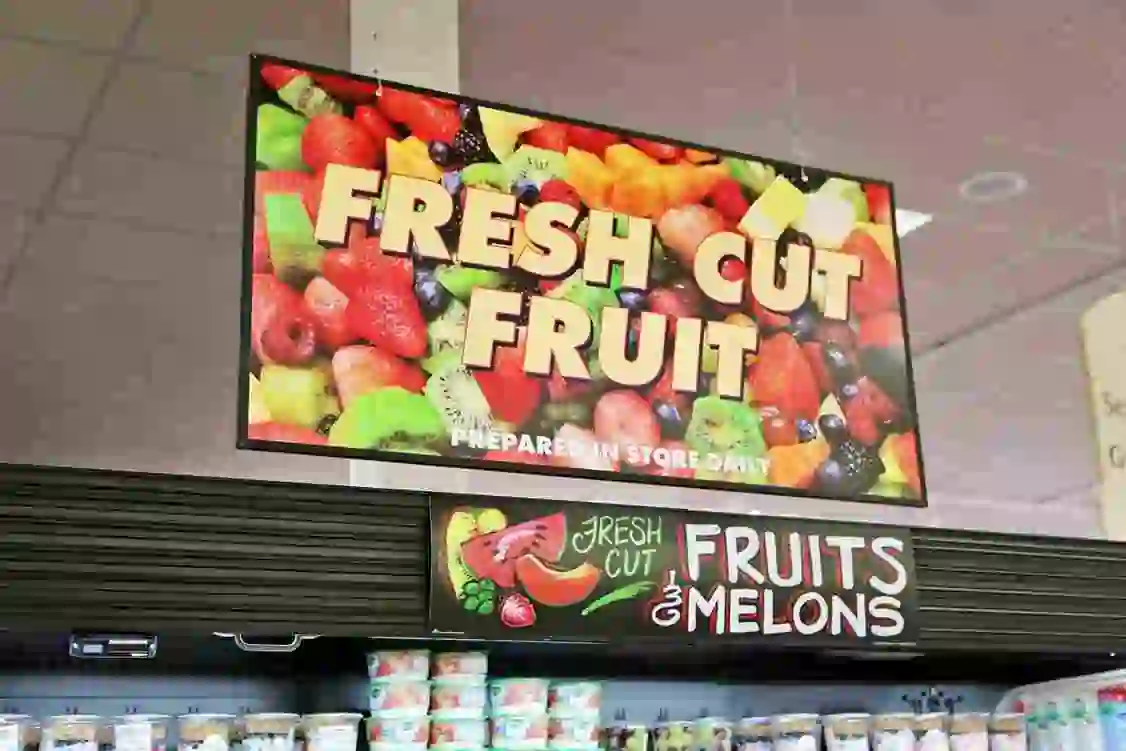 image captures a display in a store or supermarket, specifically highlighting a section dedicated to fresh-cut fruits and melons